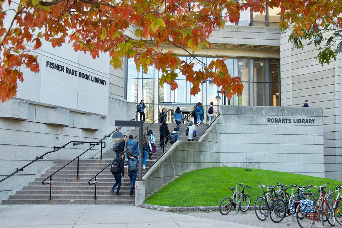 Students walk into Robarts Library with a tree in the foreground