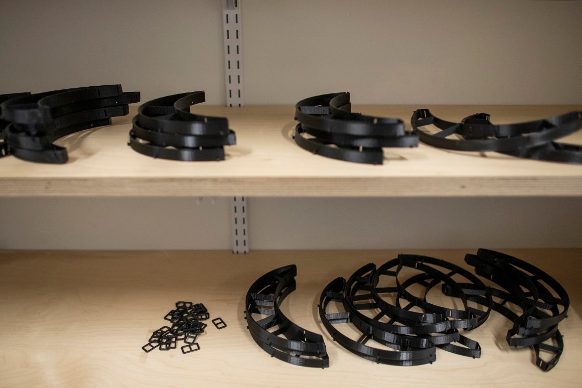 shelves holding various 3d printed parts for face shields