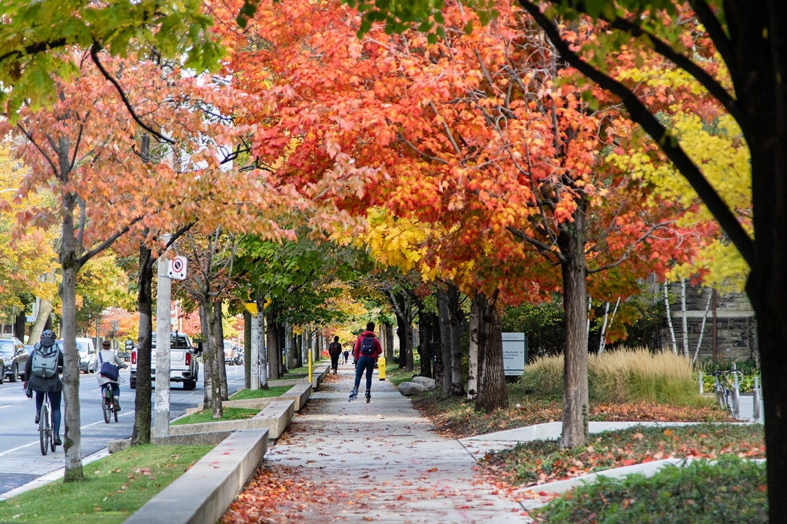 photo of students walking on campus under fall foliage