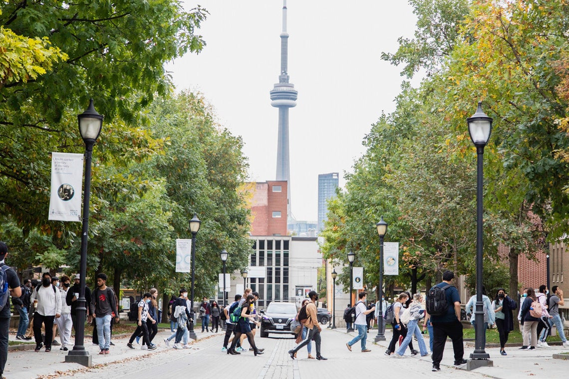 Students walk across kings college road with the CN tower in the background