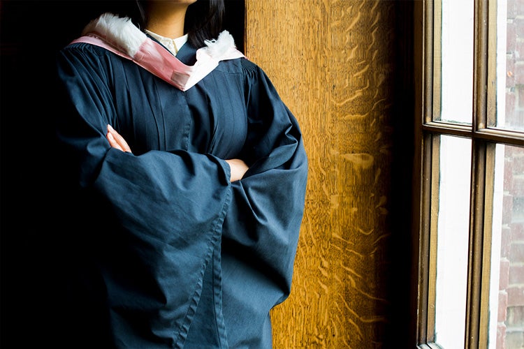 a Black woman wearing a graduation gown 