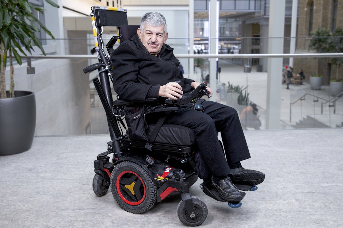 Braze Mobility smart wheelchair sensors are attached to the back and footrests of a smiling man's powered wheelchair