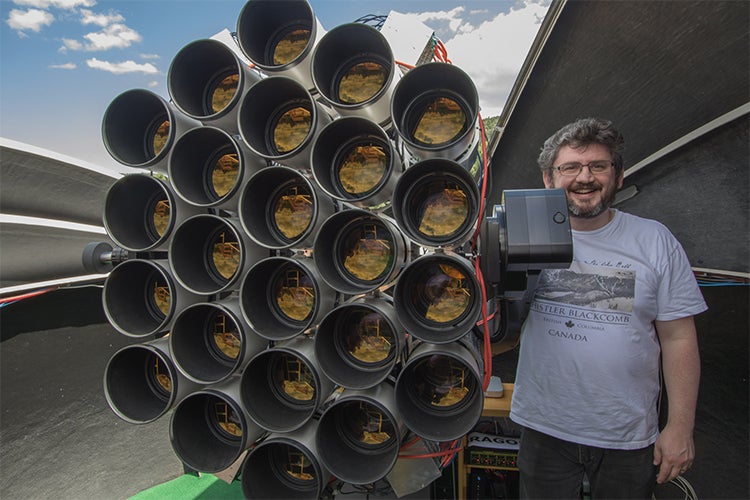 Roberto Abraham stands with one of the Dragonfly telescope arrays