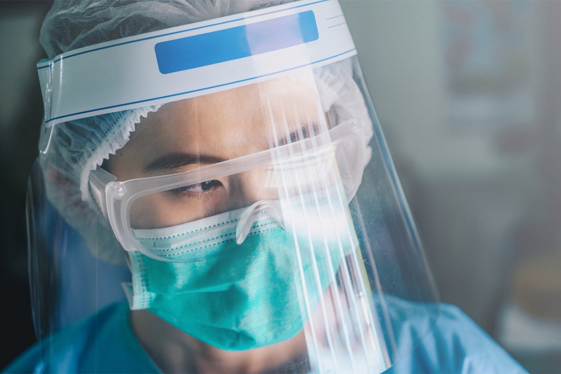 asian female nurse wearing multiple layers of PPE looking serious