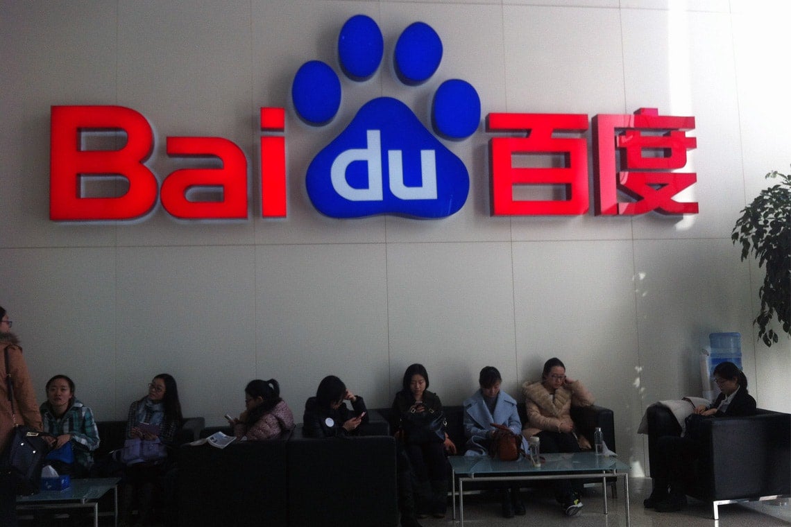 Photo of people sitting underneath a Baidu sign