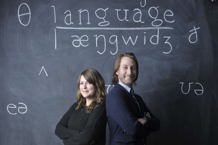 The two researchers stand with their arms crossed in front of a blackboard