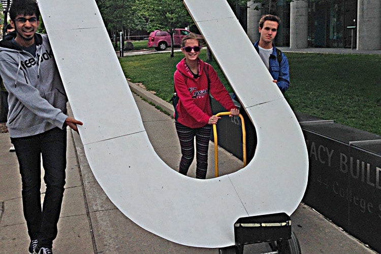 Three students carry a giant letter U