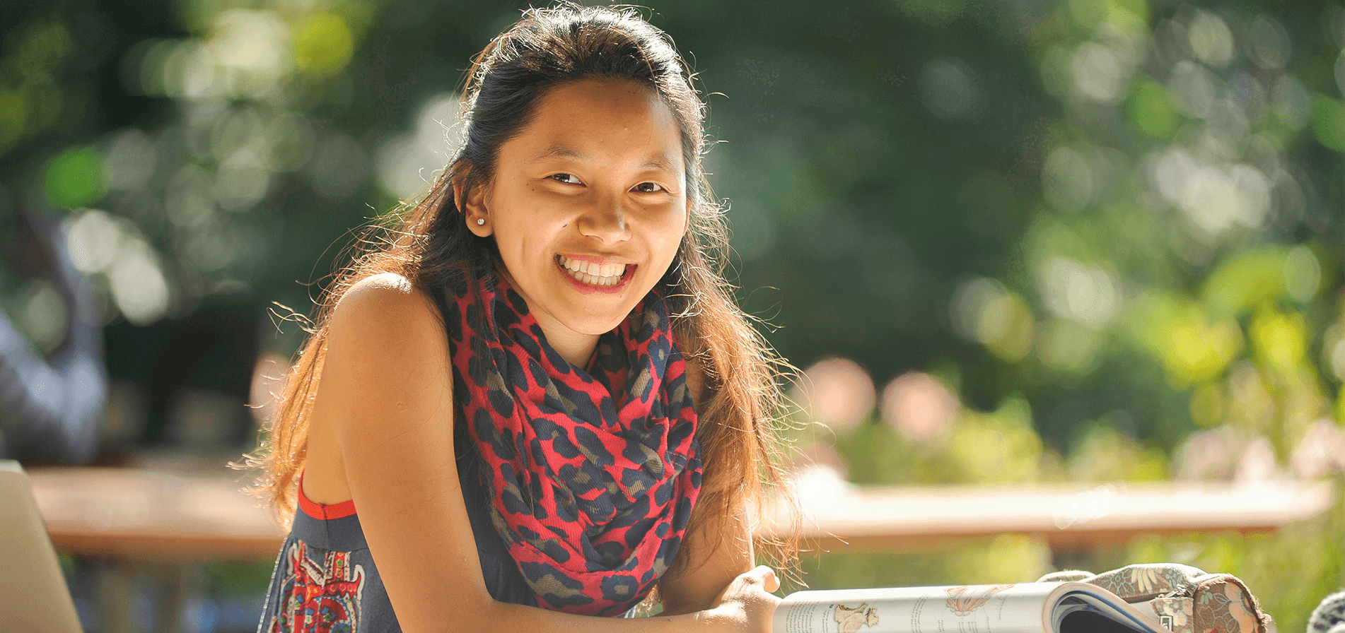 A student smiles outside while relaxing on the University of Toronto's campus.