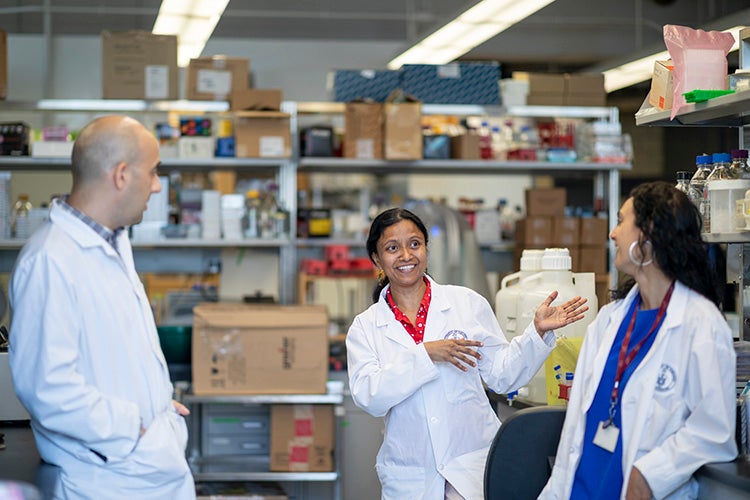 Meena Venkatesan explains something in a lab