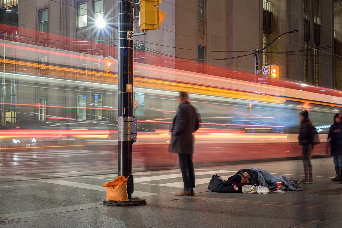 a Toronto streetcar passes by an intersection where a homeless person sleeps