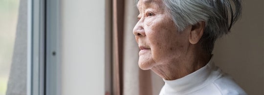 An asian woman looks out a window