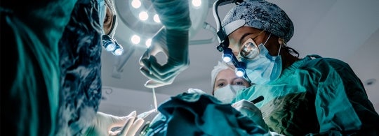 a team of three surgeons working on a patient
