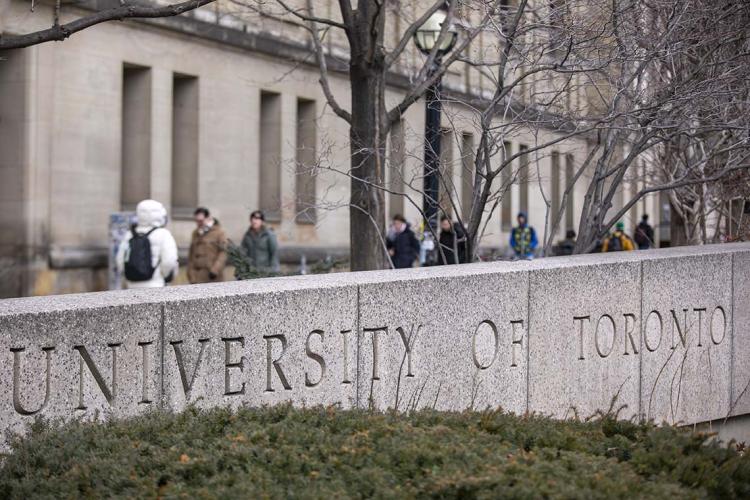 stone signage that reads "university of toronto" at the intersection of st. george st and college st in toronto