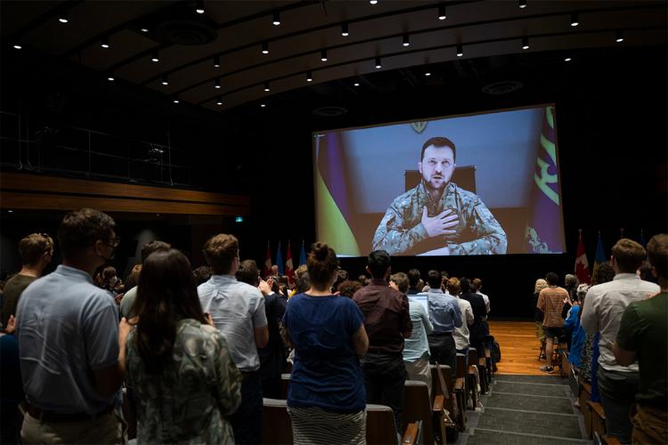 Zelenskyy puts is hand to his heart on screen while the crowd in Toronto gives him a standing ovation