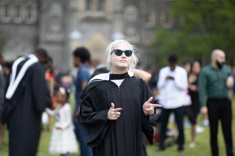 Elspeth Arbow in her graduation robe with sunglasses on and finger pointing in front of University College