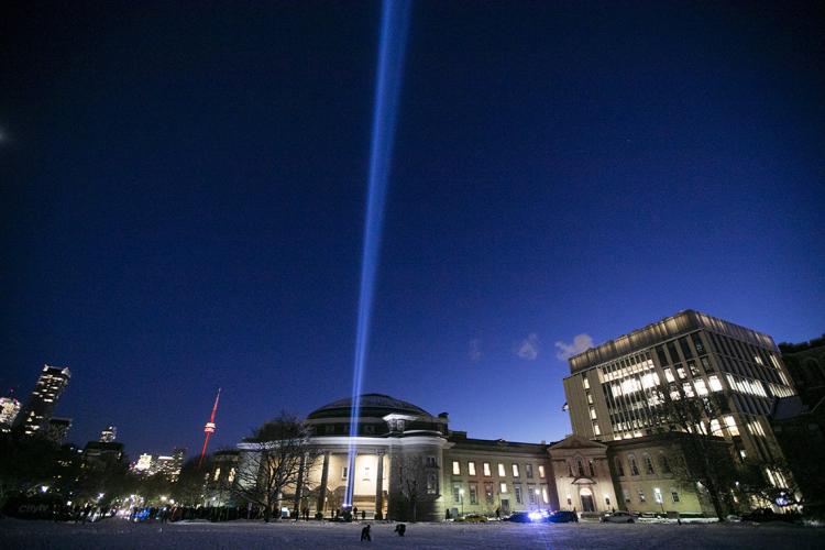 Commemorative light shines against the night sky in front of convocation hall on the National Day of Remembrance 2019