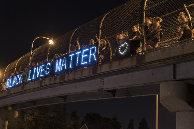 BLM supporters with a lit up Black Lives Matter sign on a bridge in Milwaukee 