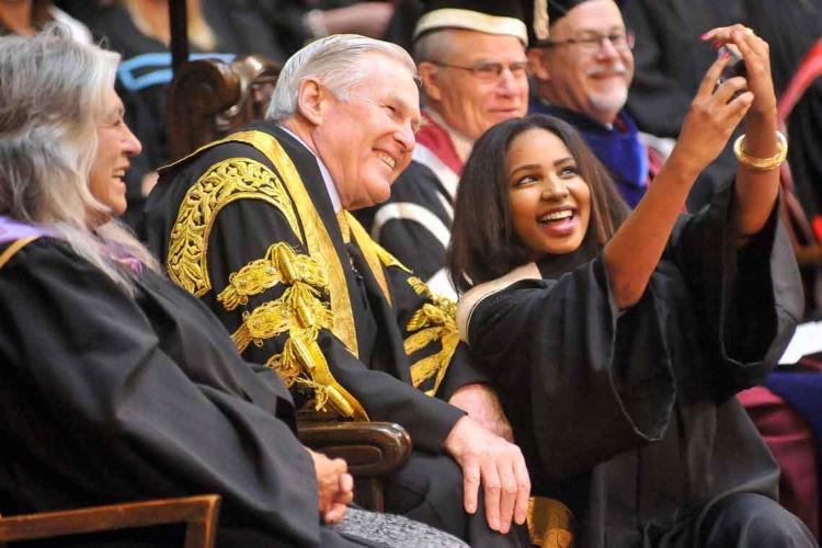 photo of graduating student taking selfie with chancellor