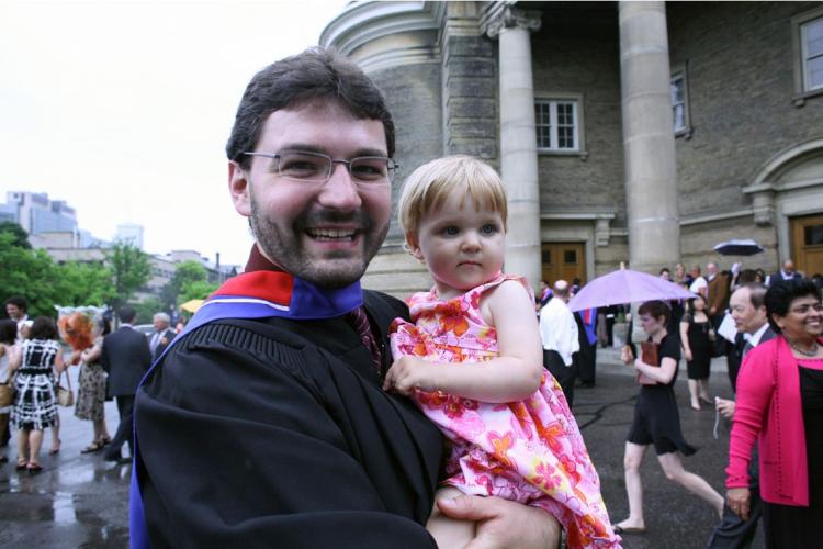 photo of grad with child in his arms