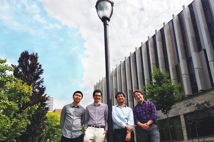 Photo of four engineering students standing by lamp post
