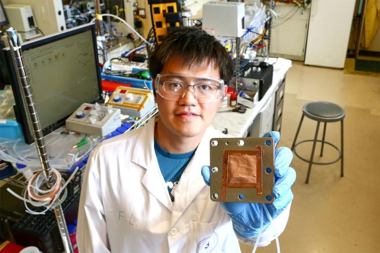 Fengwang Li is holding up an electrolyzer with a copper-based catalyst