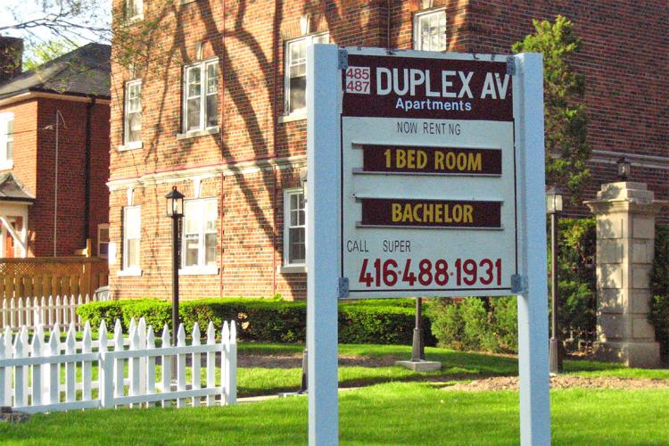 A wooden sign advertises apartments for rent in Toronto on Duplex avenue