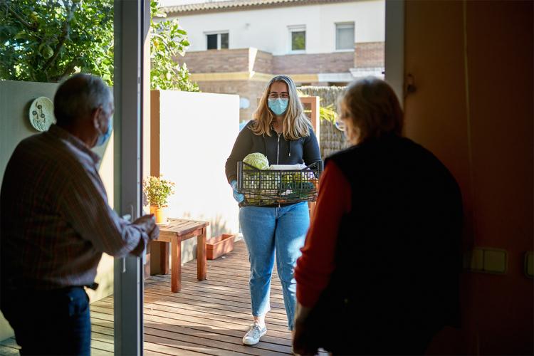 Woman delivers groceries to elderly couple