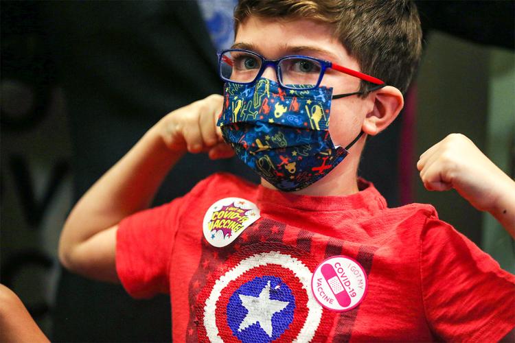 Young boy flexes his muscles after getting his first covid-19 vaccination