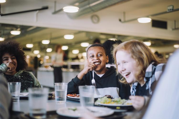 Two children eating at a cafeteria.