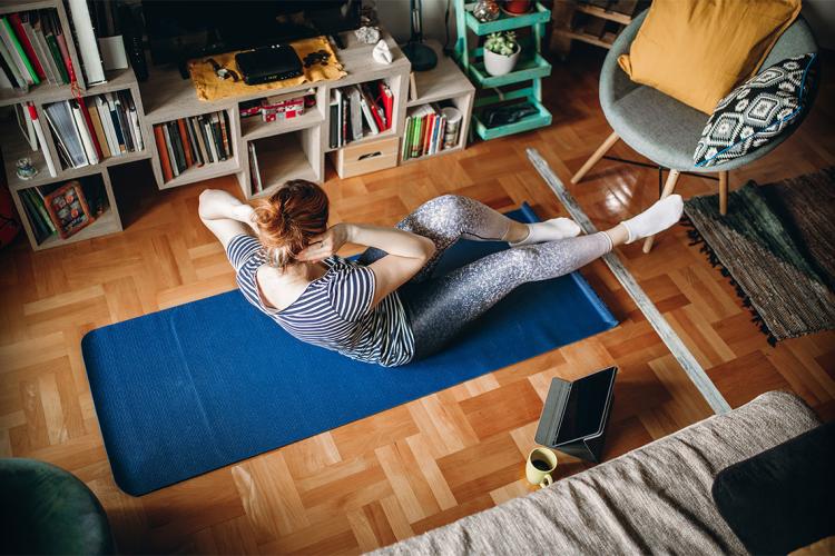 woman doing crunches on a yoga mat in her living room