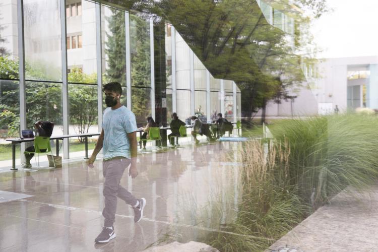 in the foreground a student walks through a hallways with students studying behind