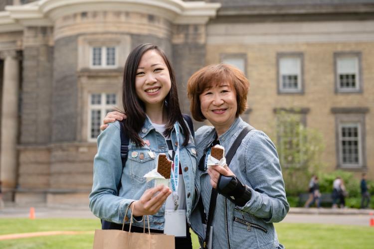 a mother and daughter enjoy an ice cream together in front of Simcoe Hall at U of T