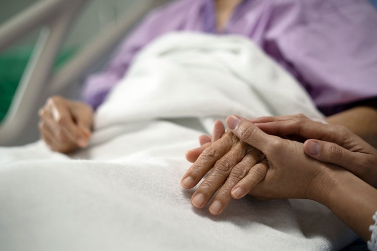 daughter holding the mother's hand and encourage while her mother sitting on bed in hospital