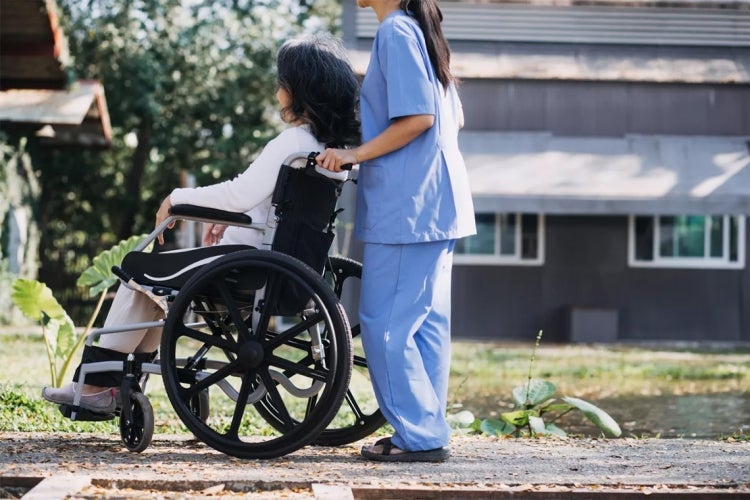 anonymous healthcare worker pushing a woman in a wheelchair