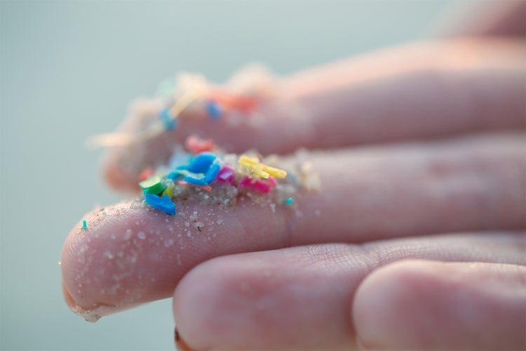 hand holding up microplastics on fingertips