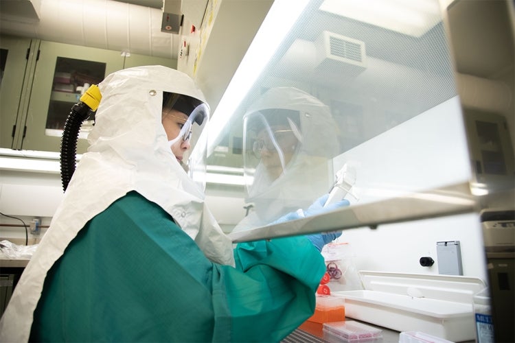 Person working under a fume hood at U of Ts Toronto High Containment Facility