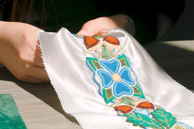 Close up of Katie Longboat's hands beading a stole