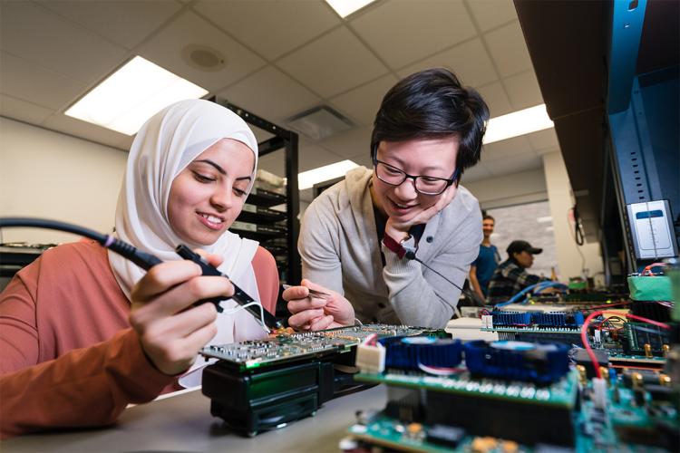 two women in a lab at the University of Toronto working on a printed circuit board
