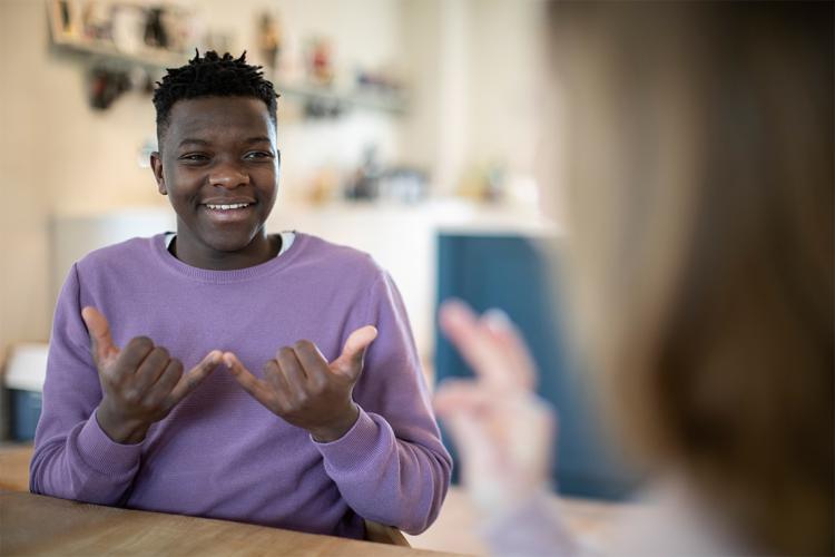 A Black youth signing "now"