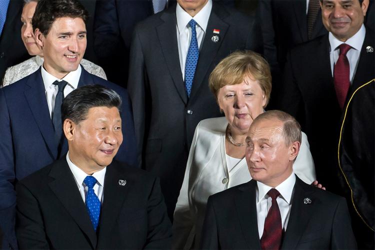 Vladirmir Putin looks back as Justin Trudeau, Angela Merkel and Xi Jinping look towards him