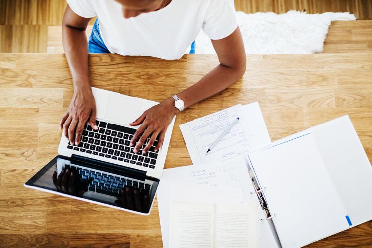 A woman works on a laptop at a table at home