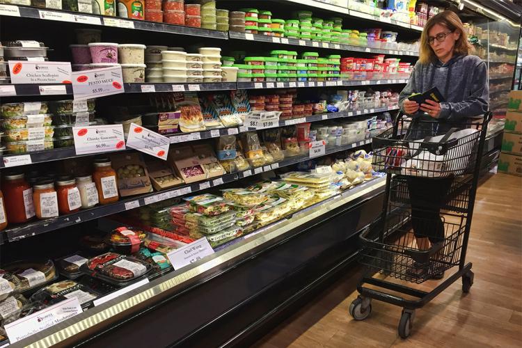a woman checks her phone while shopping in a grocery store in Toronto