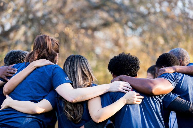 multicultural group of people linking arms in a huddle