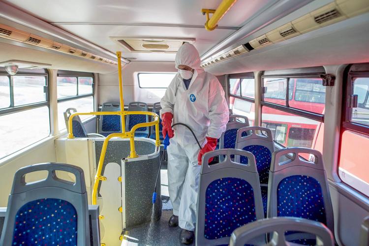 a person dressed in protective equipment sprays disinfectant on a bus in Macedonia