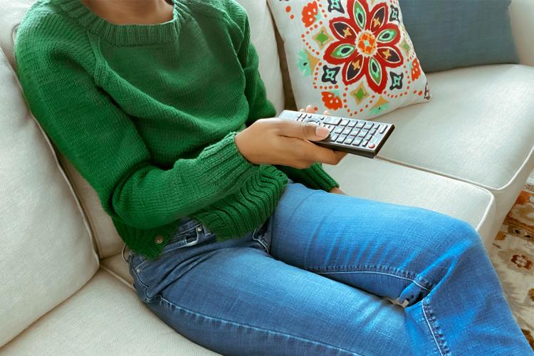 anonymous woman sitting on a sofa watching television