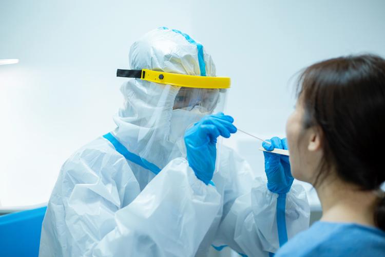 person in full protective equipment swabs a woman's mouth