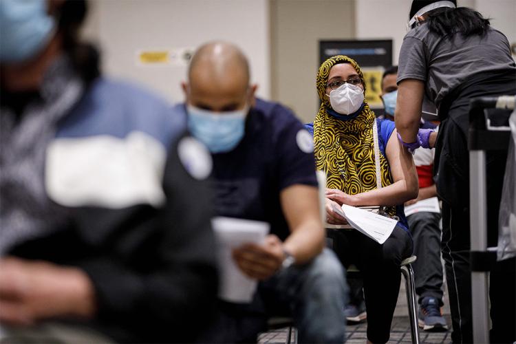 a woman in a hijab waits her turn to be vaccinated in Mississauga 