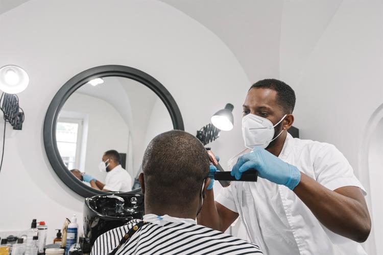 A barber cuts a man's hair with clippers