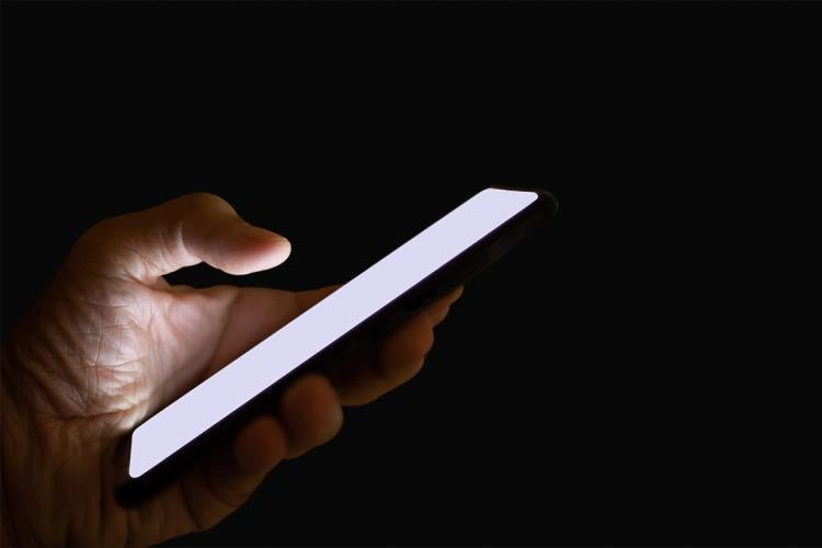 hand uses a smartphone in the dark