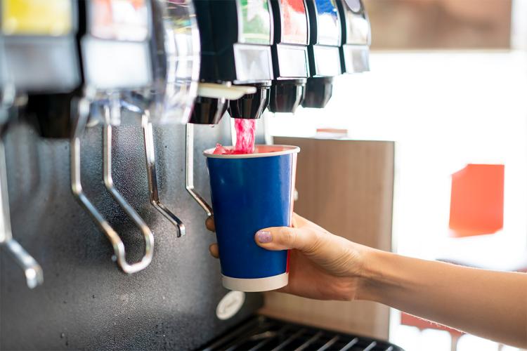 A consumer uses a soda fountain to fill a cup